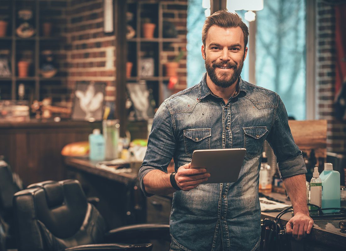 Business Insurance - Portrait of a Business Owner Holding a Digital Tablet in His Workshop